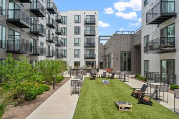 an open courtyard with lawn chairs and tables in front of an apartment building